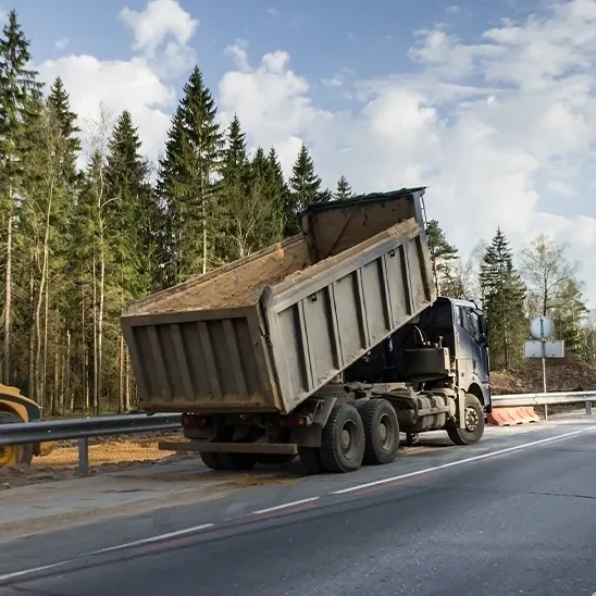 A dump truck is driving down the road.